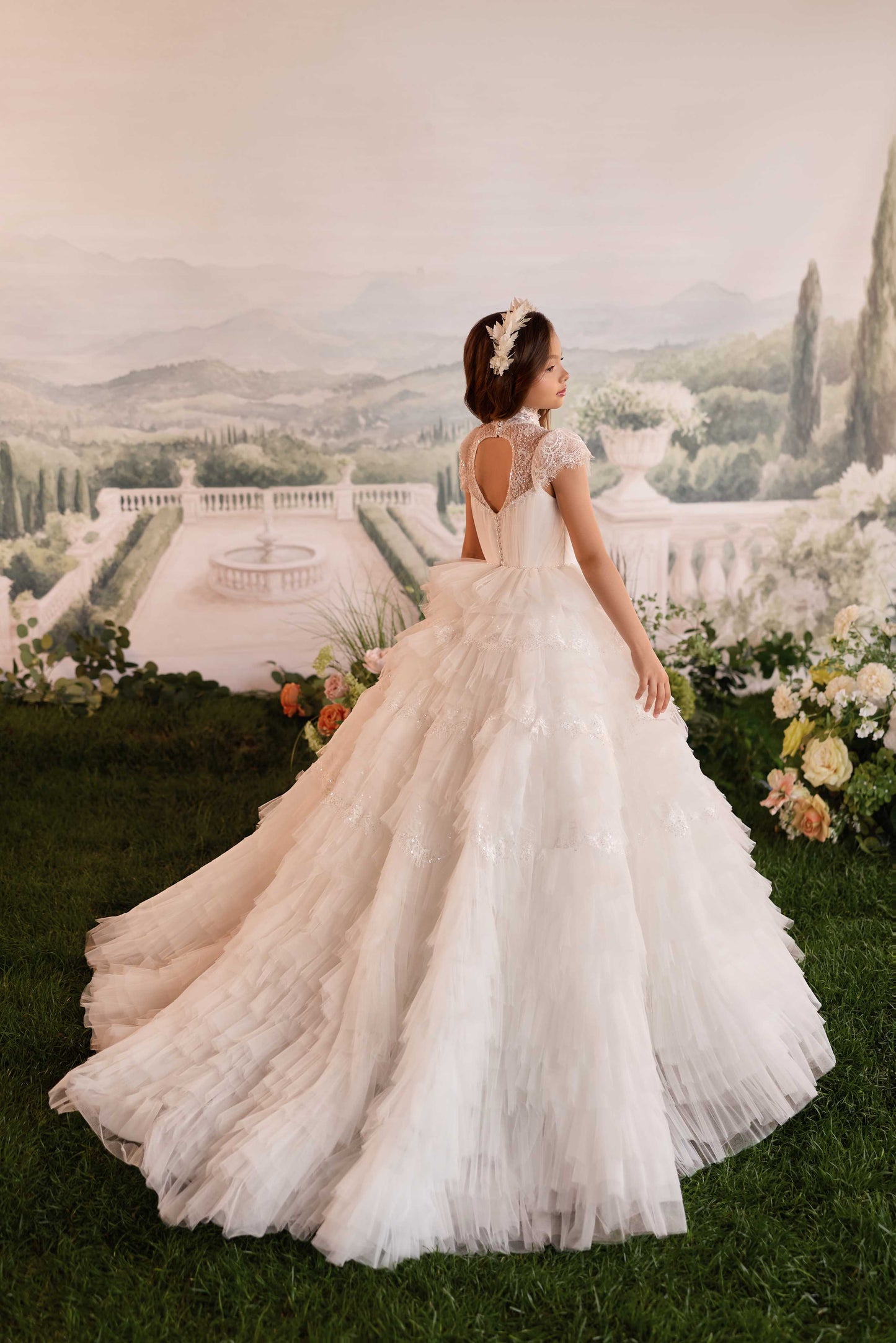 Back view of a premium white flower girl gown showing a majestic, tiered pleated tulle sweeping train.