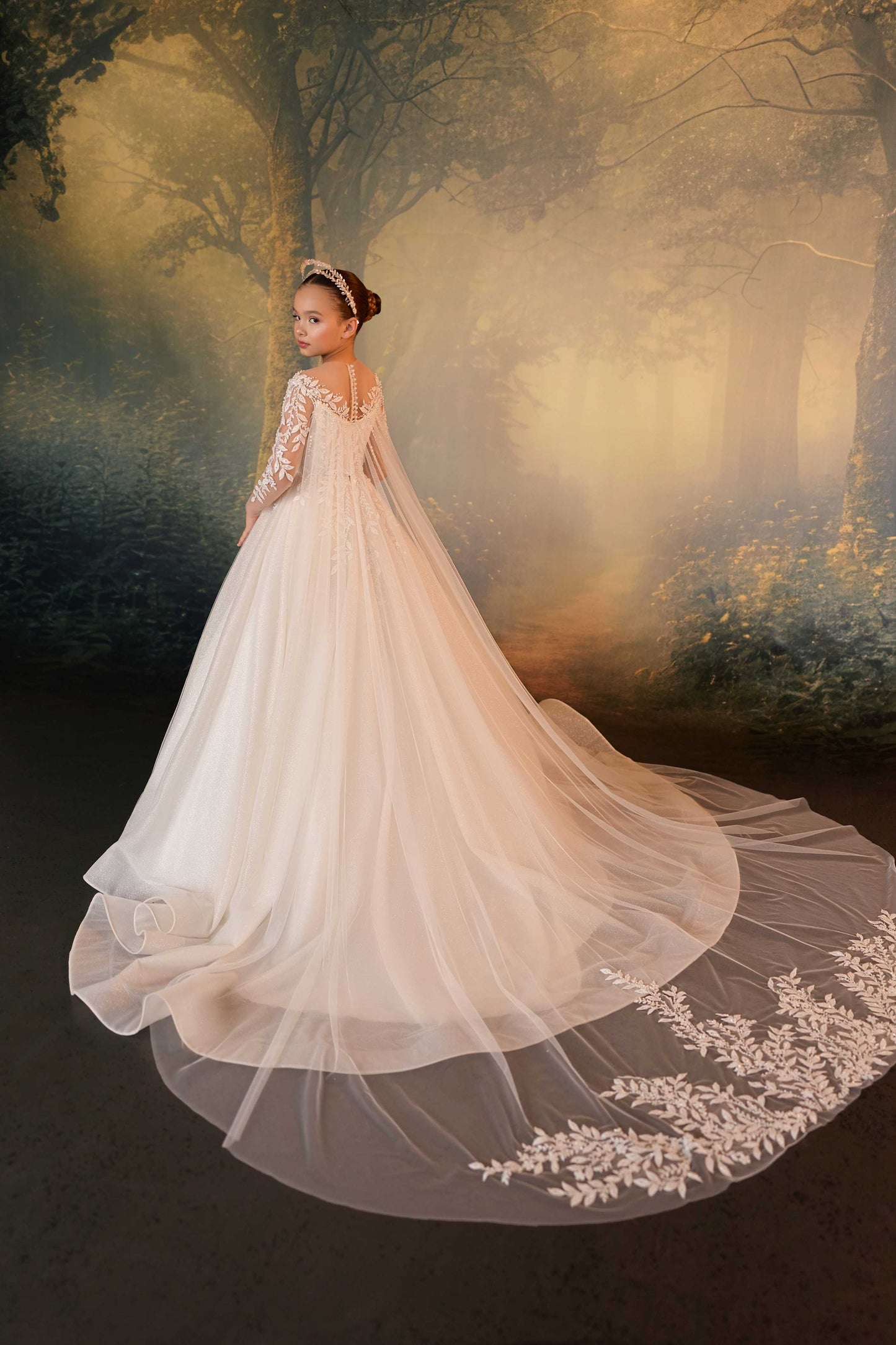 Back view of a premium children's formal gown showing a long sparkling tulle train with lace trim.