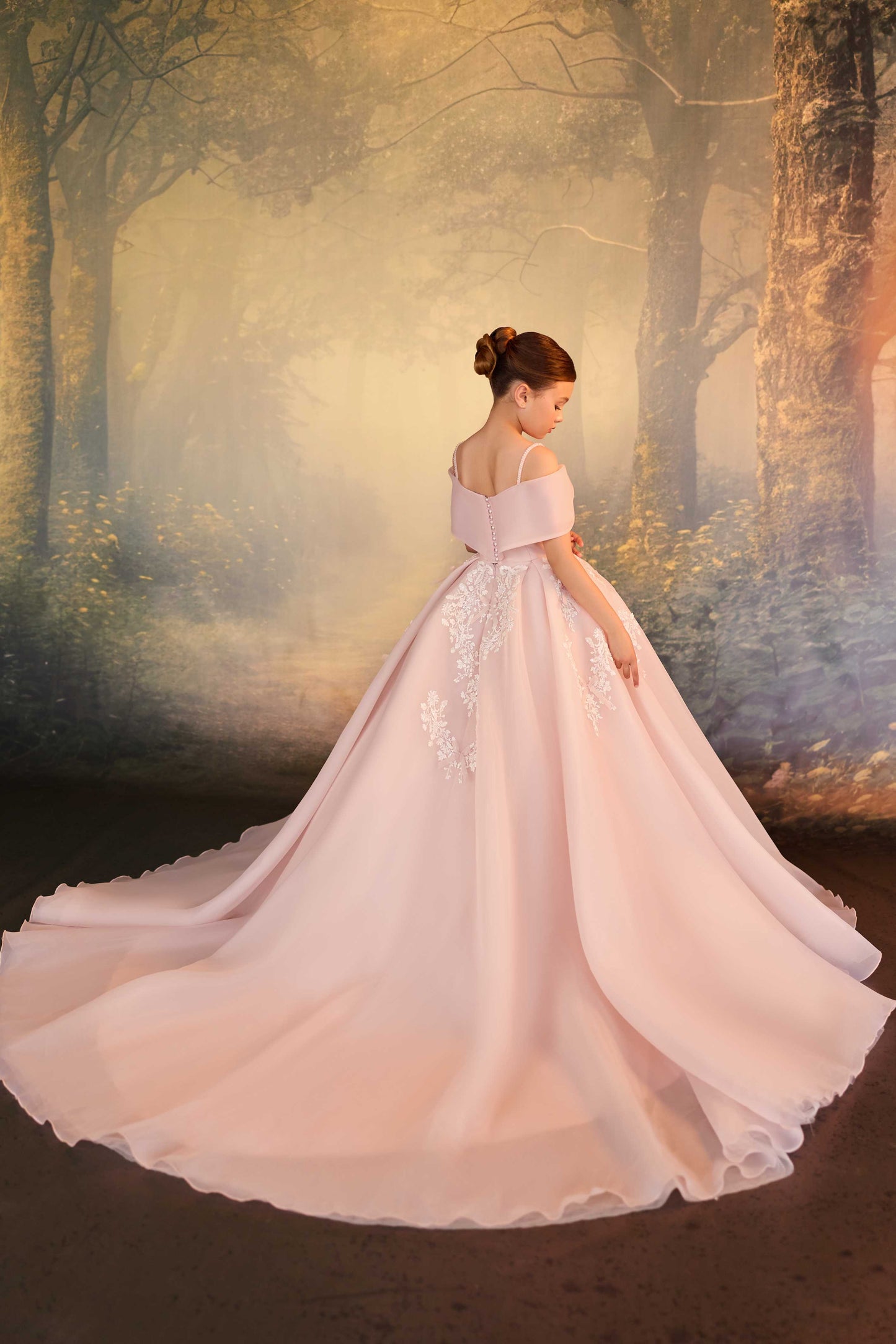 Little girl wearing a blush pink off-shoulder ball gown with an oversized bow bodice and white floral lace embroidery.