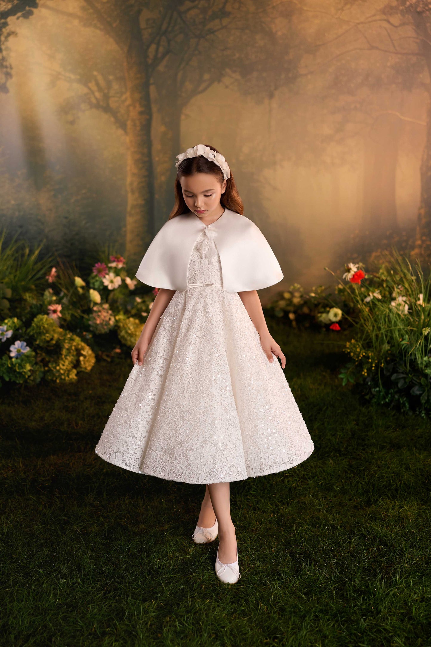 ull-length front view of a girl wearing a white textured A-line Communion dress with a matching capelet 