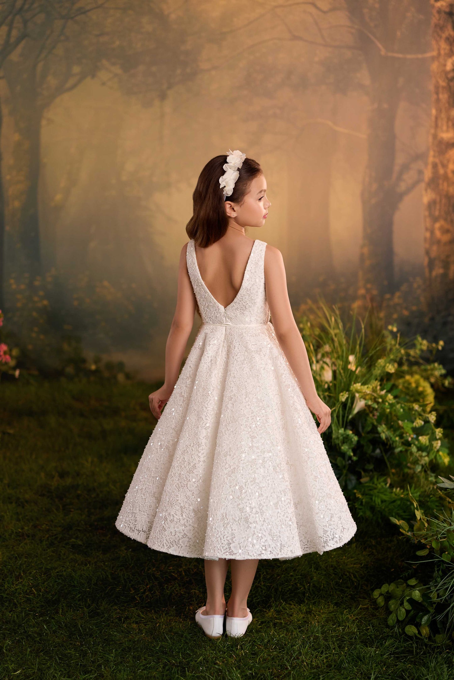 oung girl twirling to show the volume and movement of the tea-length skirt on a white textured special occasion dress.