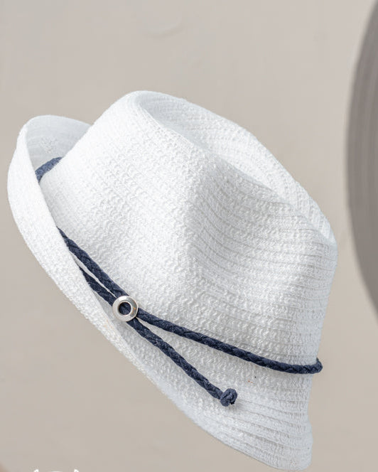 A white straw hat with navy band and pearl accent on a beige background, 